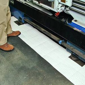 A factory employee deploying the N-FIBER R508 to contain an oil leak on the floor and machinery parts
